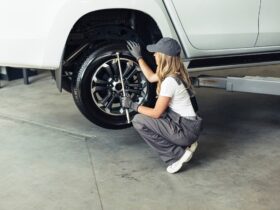 Egy nő munkaruhában gumit cserél.